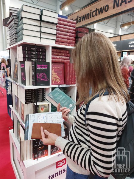 Biblioteka Gorlice, Targi Książki 2025 bibliotekarka ogląda książkę