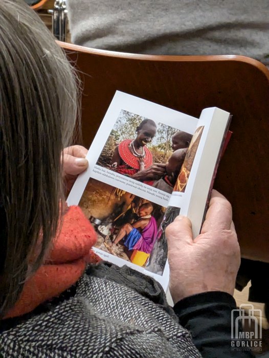 Biblioteka Gorlice, „Mój przyjaciel Masaj” — spotkanie autorskie z Elżbietą Wiejaczką uczestniczka spotkania przegląda książkę otwartą na ilustracjach