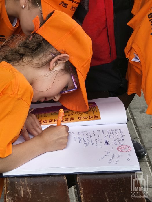 Biblioteka Gorlice, Odjazdowy Bibliotekarz dziewczynka - uczestniczka rajdu wpisuje się do pamiątkowej ksiegi
