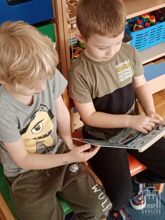 przedszkolaki ogladaja książkę z biblioteki