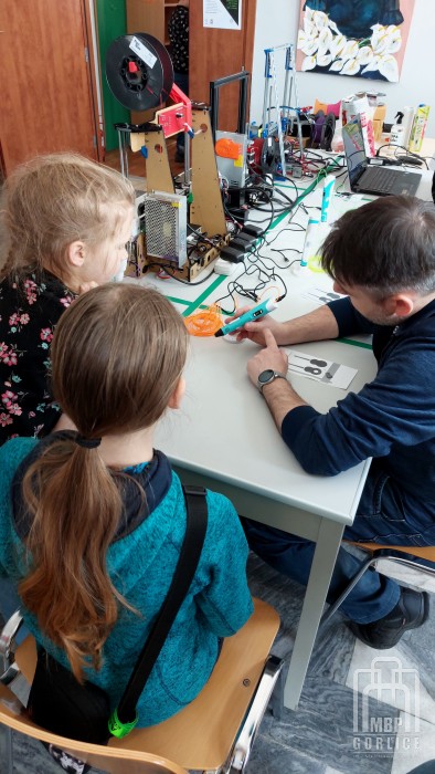 organizator pokazuje dzieciom jak używać długopisu 3D