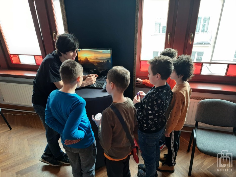 Organziator przedstawia grupce dzieci mikrokomputer Rapsberry Pi