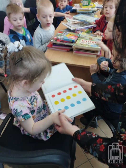 dzieci naciskaja kolorowe kółka w książce