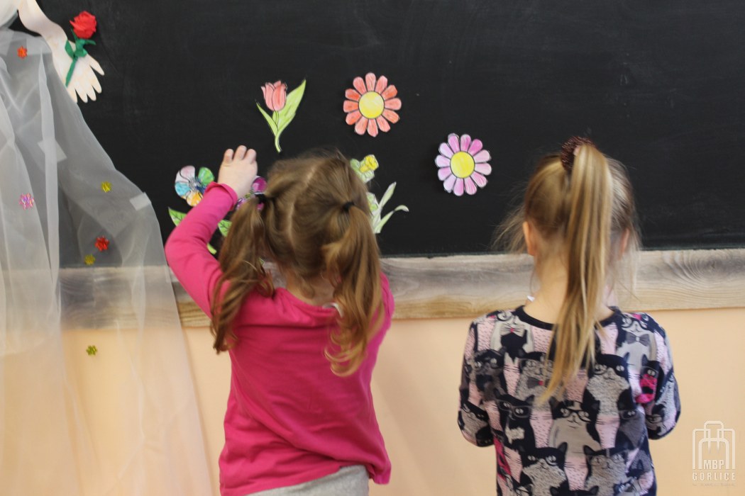 0735 – dzieci dekorują kwiatami tablicę z wizerunkiem pani wiosny